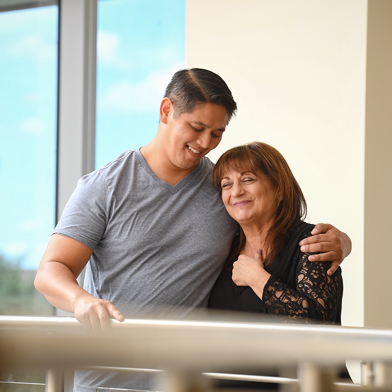 A man and woman embrace on a balcony after donating to a community wellness program