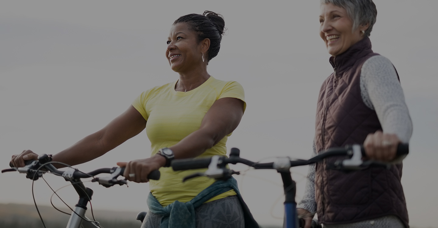 Two women enjoy biking outside as part of a healthy weight loss program