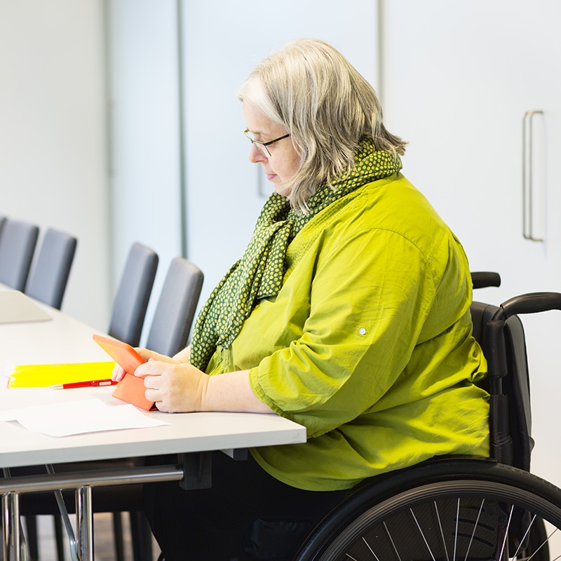 Woman in a wheelchair volunteering her time to help people register for health programs and classes