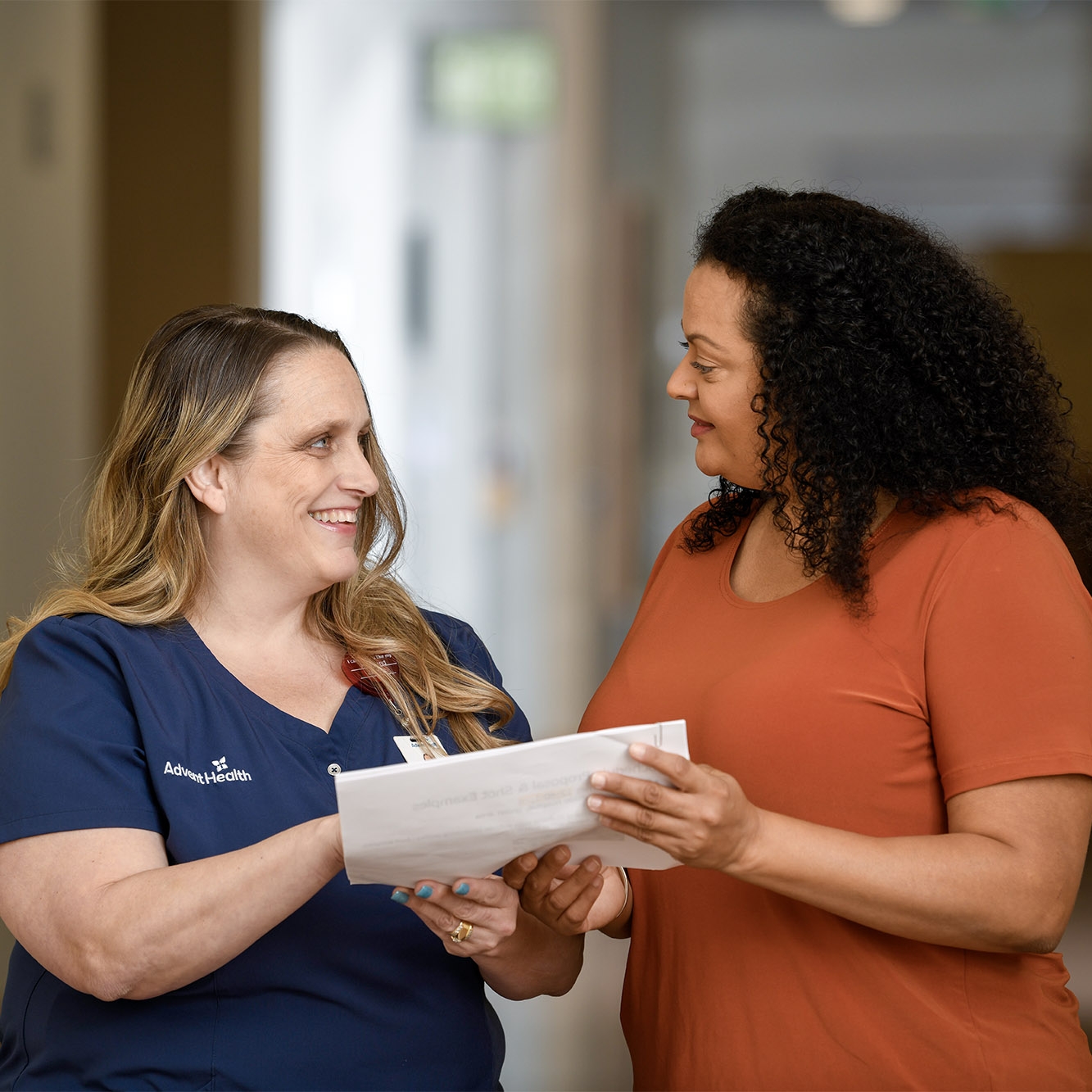 A woman reviewing medical documents with her nurse.